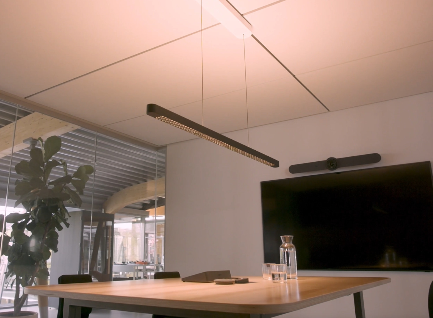 Arbeitsbereich mit Tisch, Bildschirm und lichtstarker Pendelleuchte