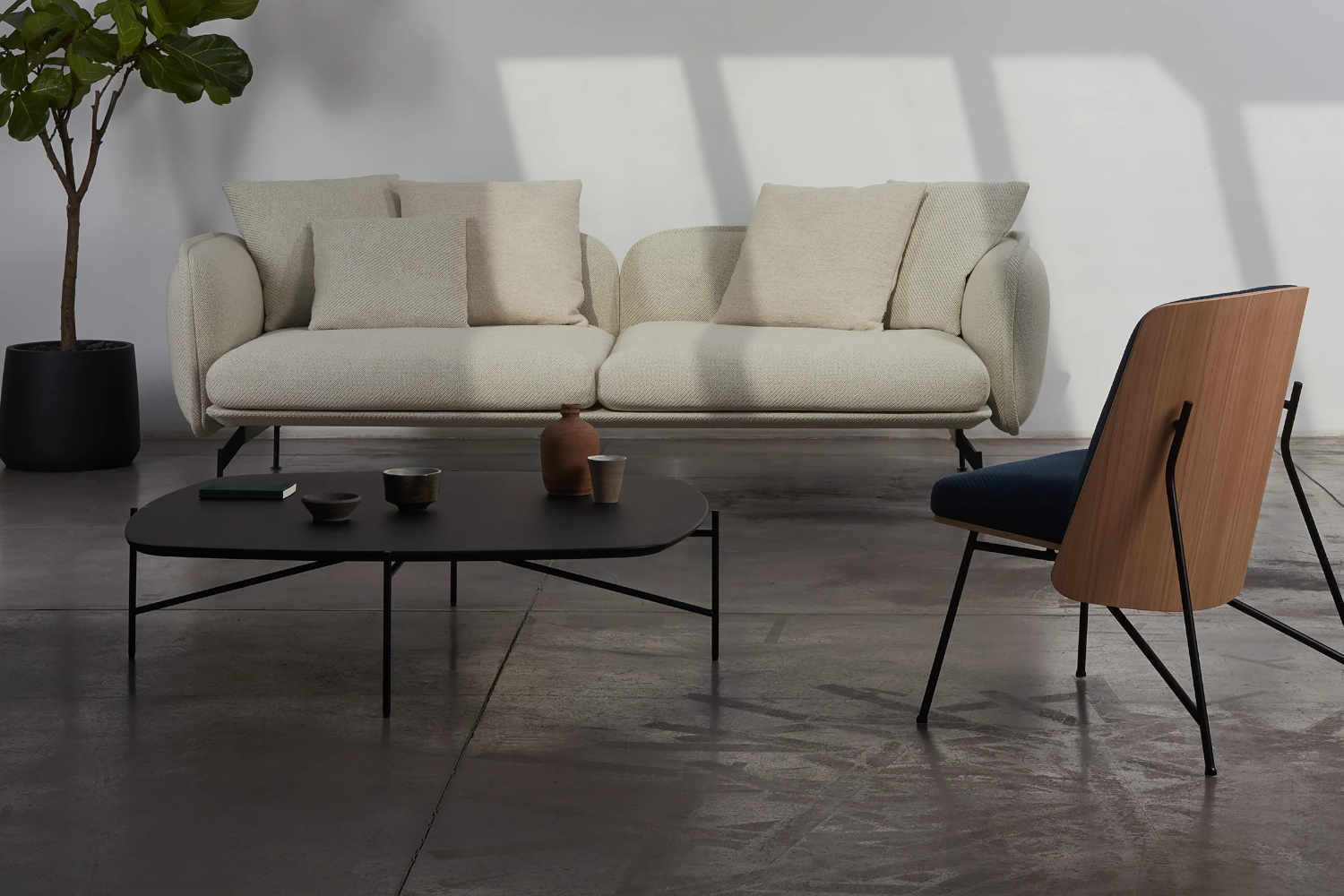 Ein Sofa Echo von Prostoria steht neben einem Beistelltisch und Sessel
